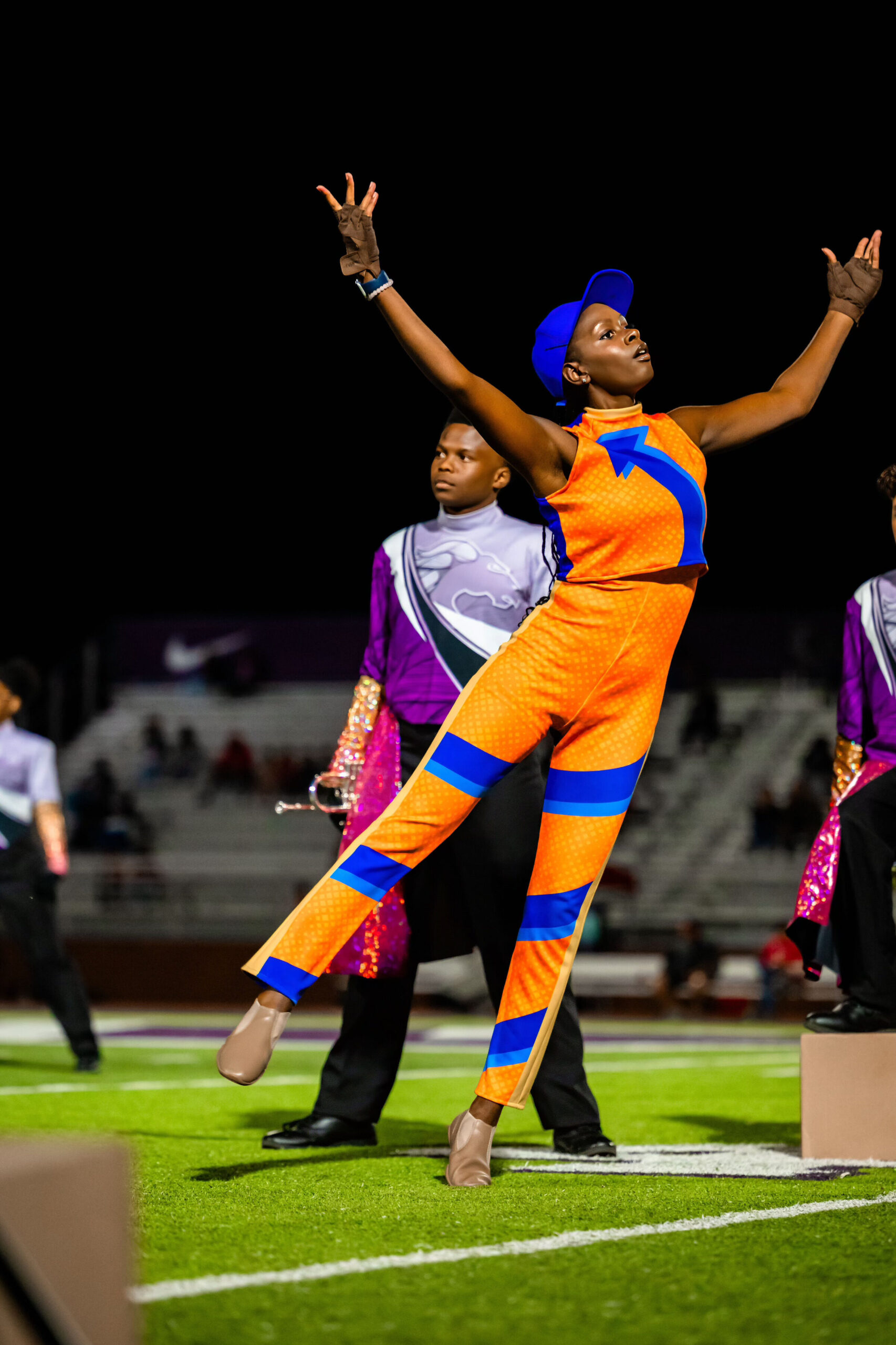 color guard girl dances with her arms and right leg lifted left leg on releve